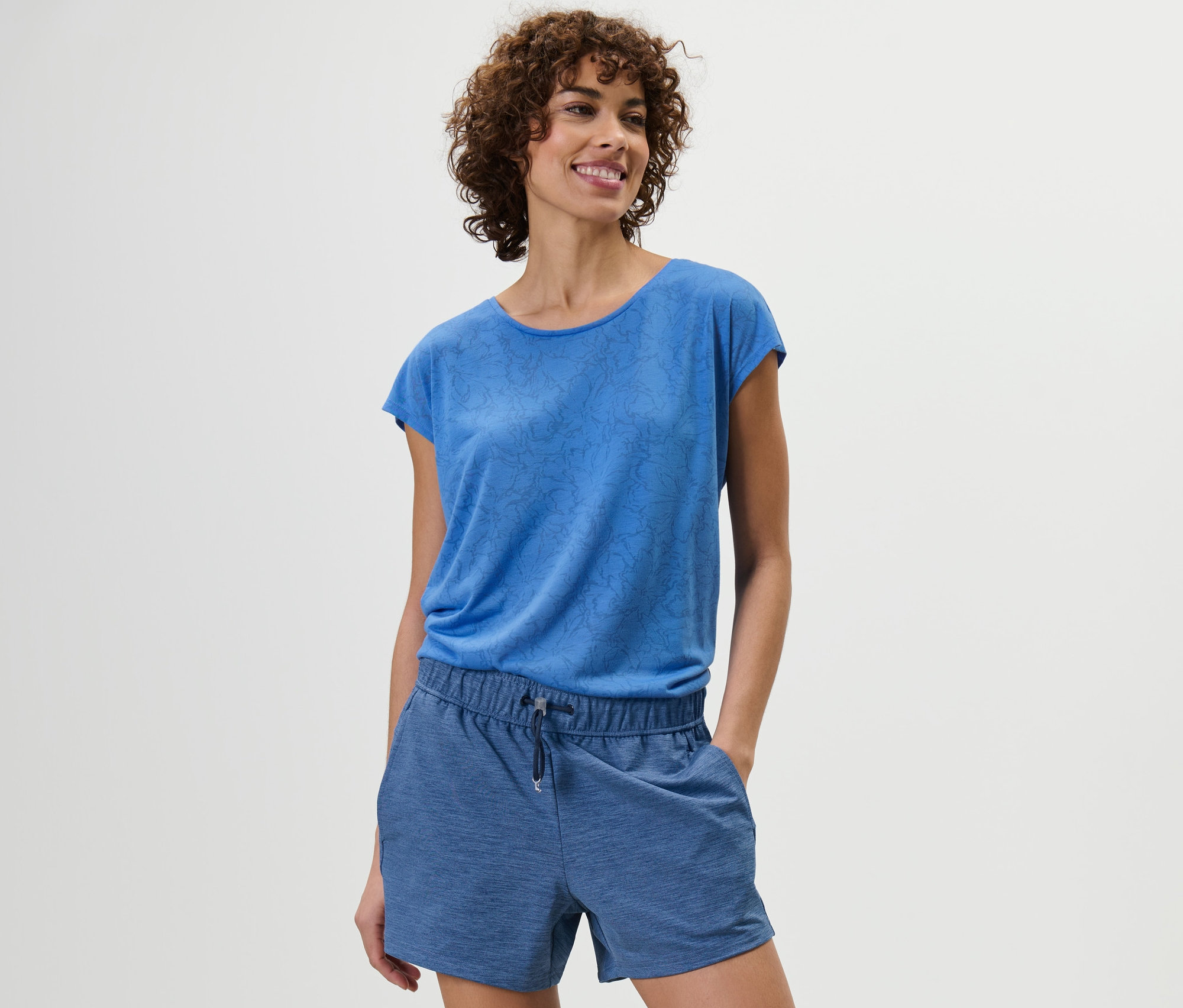 Frau posiert in blauen Funktionsshorts und blauem Oberteil.
