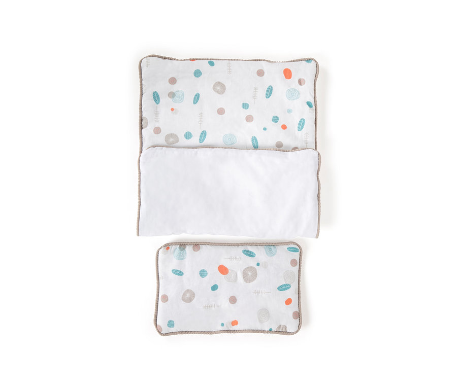 Kissen und Bettdecke mit Blätter- und Punktmuster auf weißem Hintergrund.