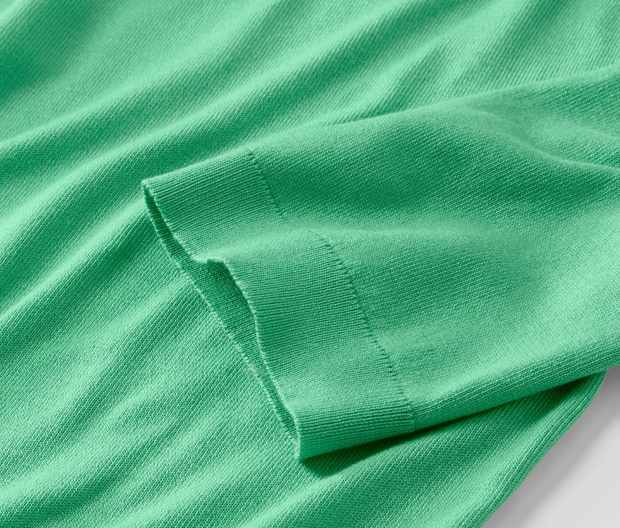 Detailaufnahme eines grünen Feinstrickpullovers.