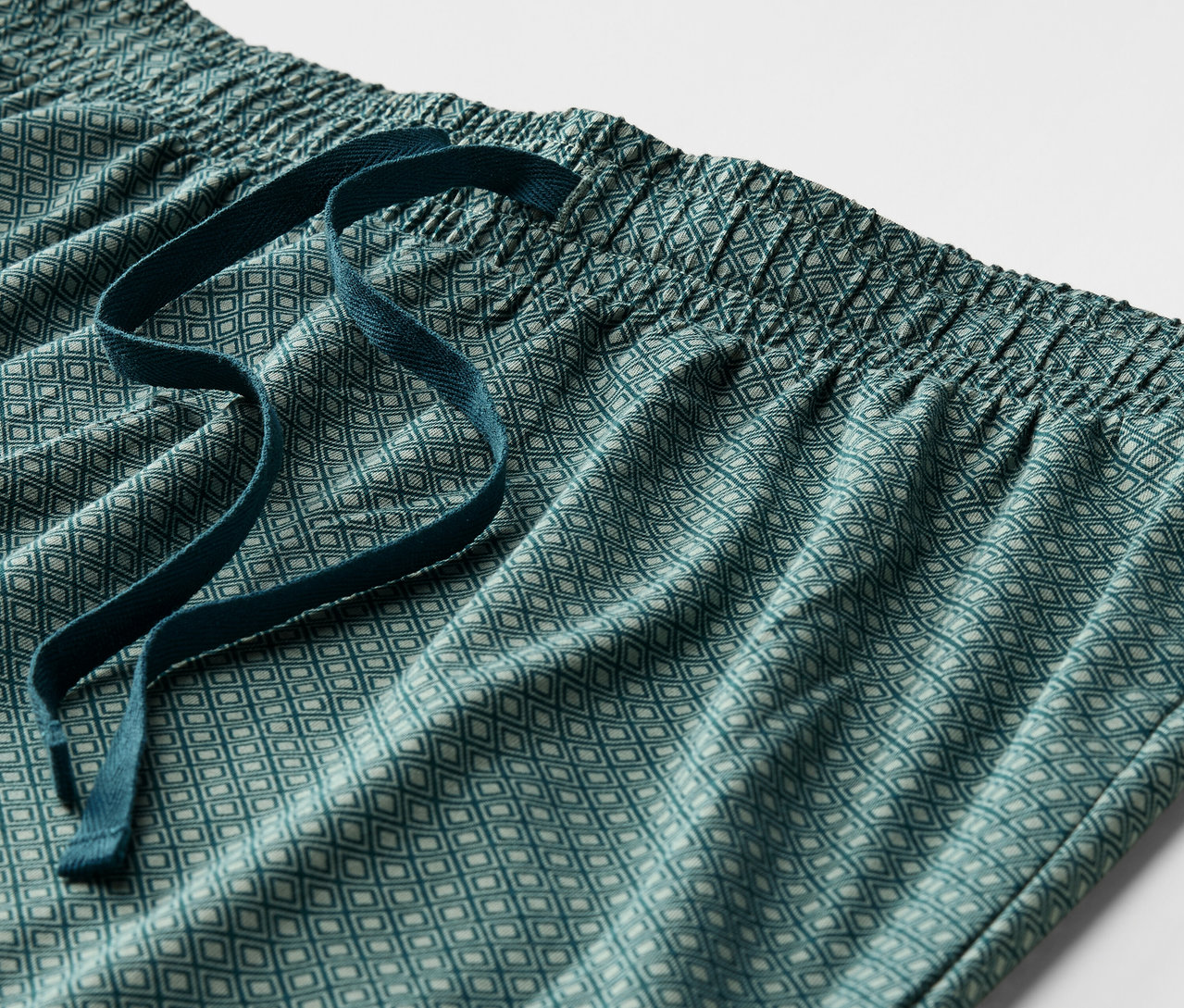 Detail einer grünen, gemusterten Pyjamahose mit elastischem Bund und Kordelzug.