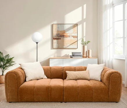 Ein braunes Sofa mit zwei beige Kissen in einem Wohnzimmer.