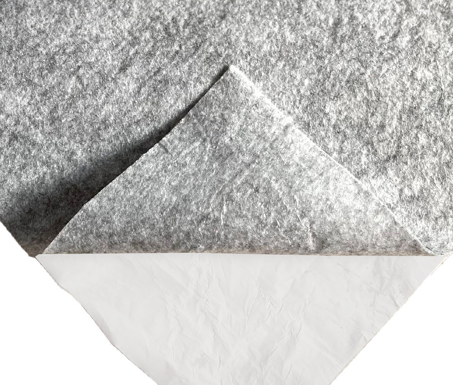 Graues Textil mit hochgeklappter Ecke, die eine weiße Unterlage freilegt.