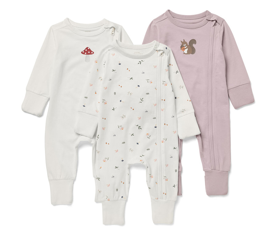 Drei langärmelige Baby-Overalls. Einer ist weiß mit einem Fliegenpilz, einer mit einem Blumenmuster und einer ist lila mit einem Eichhörnchen.