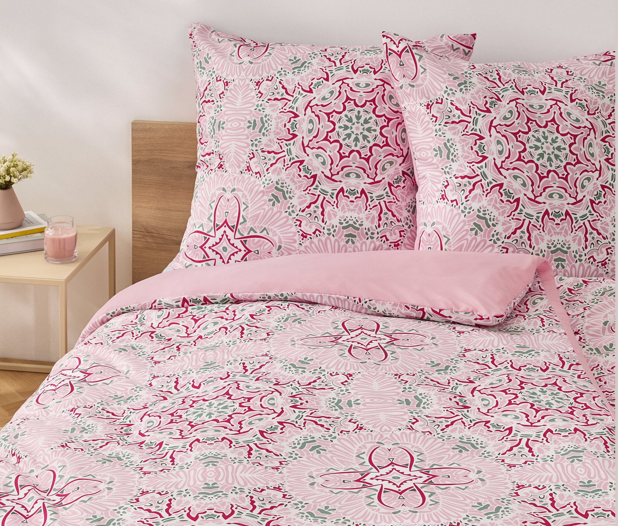 Rosa Microfaser-Bettwäsche in Normalgröße mit Blumenmuster auf einem Bett.