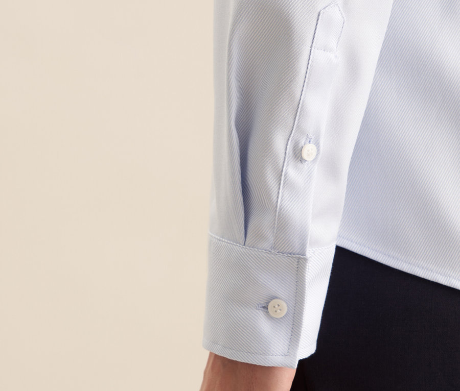 Detailansicht einer hellblauen Seidensticker Twillbluse mit Hand.