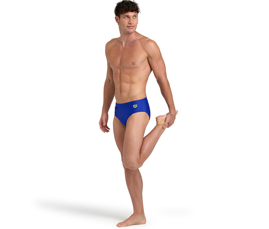Mann dehnt Bein in blauer Badehose, arena Badehose Slip Zip.