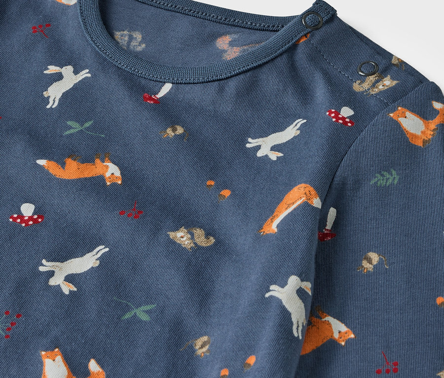 Detailaufnahme eines blau-grünen Kinder-Pyjama-Sets mit Fuchs- und Hasenmuster.