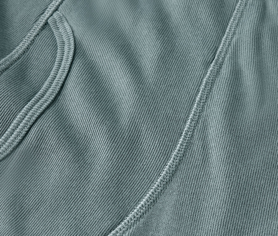 Detailaufnahme eines blaugrünen Stoffes mit Tasche und Naht.