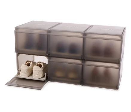 Sechs graue Joseph Joseph Premium-Schuhaufbewahrungsboxen sind übereinander gestapelt, eine Box ist offen und enthält beige Schuhe.