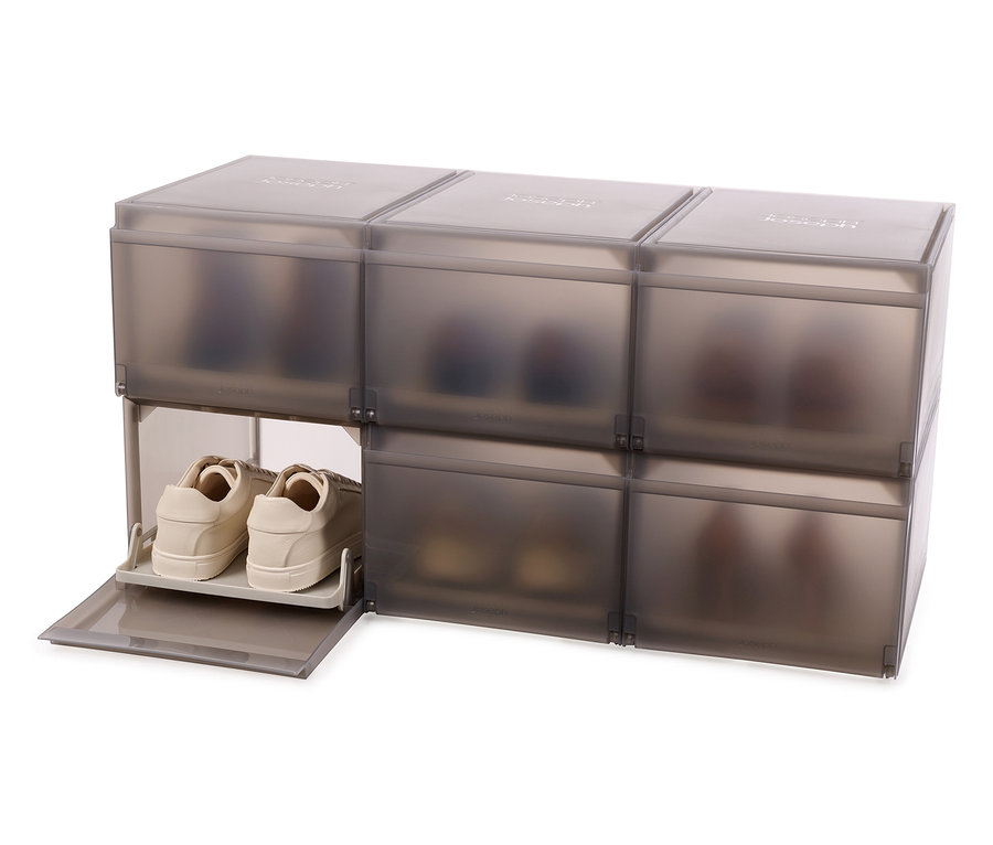 Sechs graue Joseph Joseph Premium-Schuhaufbewahrungsboxen sind übereinander gestapelt, eine Box ist offen und enthält beige Schuhe.
