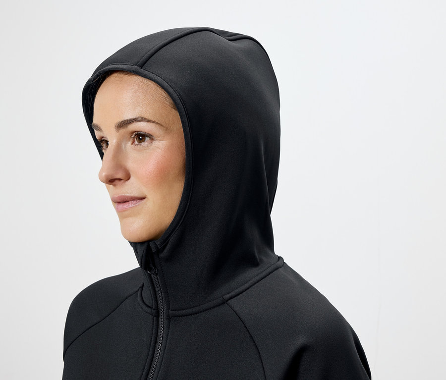 Frau mit braunen Haaren trägt einen schwarzen Kapuzenpullover.