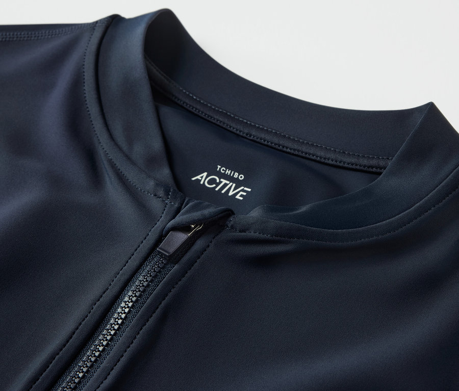 Nahaufnahme eines UV-Schutz-Sportshirts mit teilweise geöffnetem Reißverschluss.