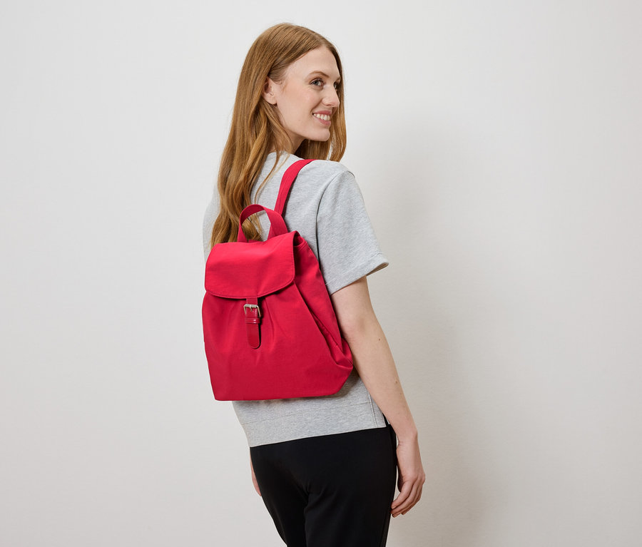 Frau mit rotem Rucksack auf dem Rücken, blickt nach links.