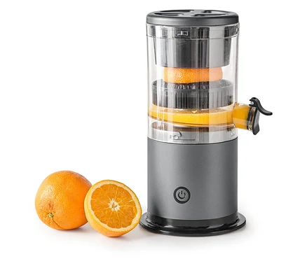 Orangen werden in einem grauen Entsafter entsaftet, daneben liegen eine ganze und eine halbe Orange.