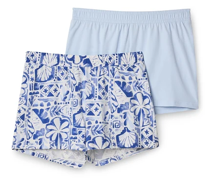 Zwei Shorts, eine hellblaue unifarbene und eine weiß-blaue gemusterte mit Muschel- und Blättermotiven, liegen übereinander.