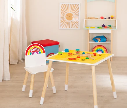 Ein Play-Doh-Tisch mit Stuhl und Regal in einem Spielzimmer. Auf dem Tisch liegen Play-Doh-Dosen und Werkzeuge.