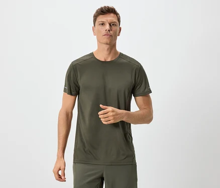 Mann in olivgrünem T-Shirt und Shorts vor neutralem Hintergrund.