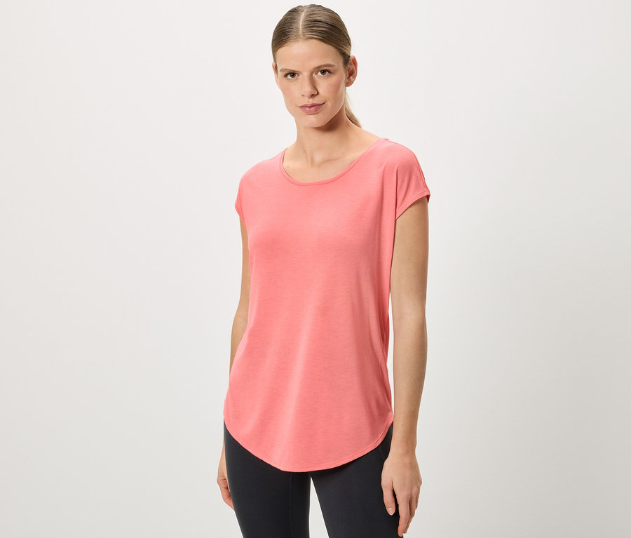 Frau mit Pferdeschwanz trägt ein korallfarbenes T-Shirt und schwarze Leggings.