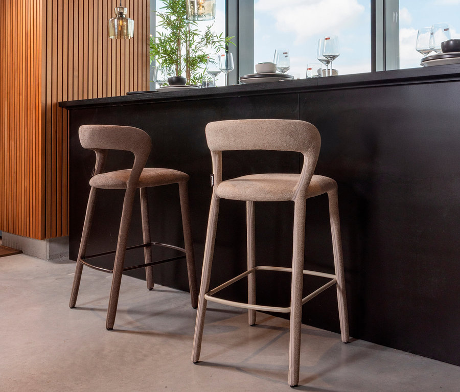 Zwei Barhocker stehen an einer Küchentheke vor einem Fenster.