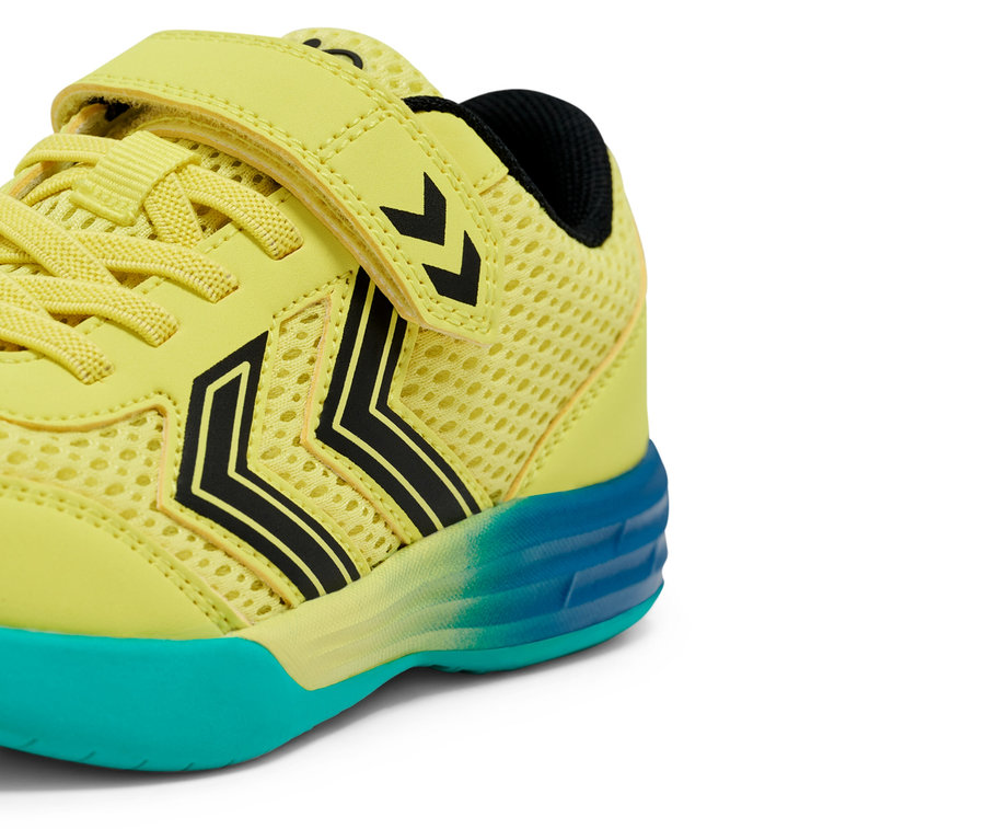Nahaufnahme eines hellgelben Kinder Sportschuhs mit Klettverschluss und schwarzen Hummel-Winkeln, die Sohle ist türkis.