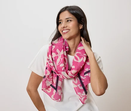 Frau mit einem pinkfarbenen Schal mit Blumenmuster und einem weißen T-Shirt.
