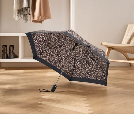 Geöffneter Regenschirm mit Leopardenmuster steht auf einem Holzboden.