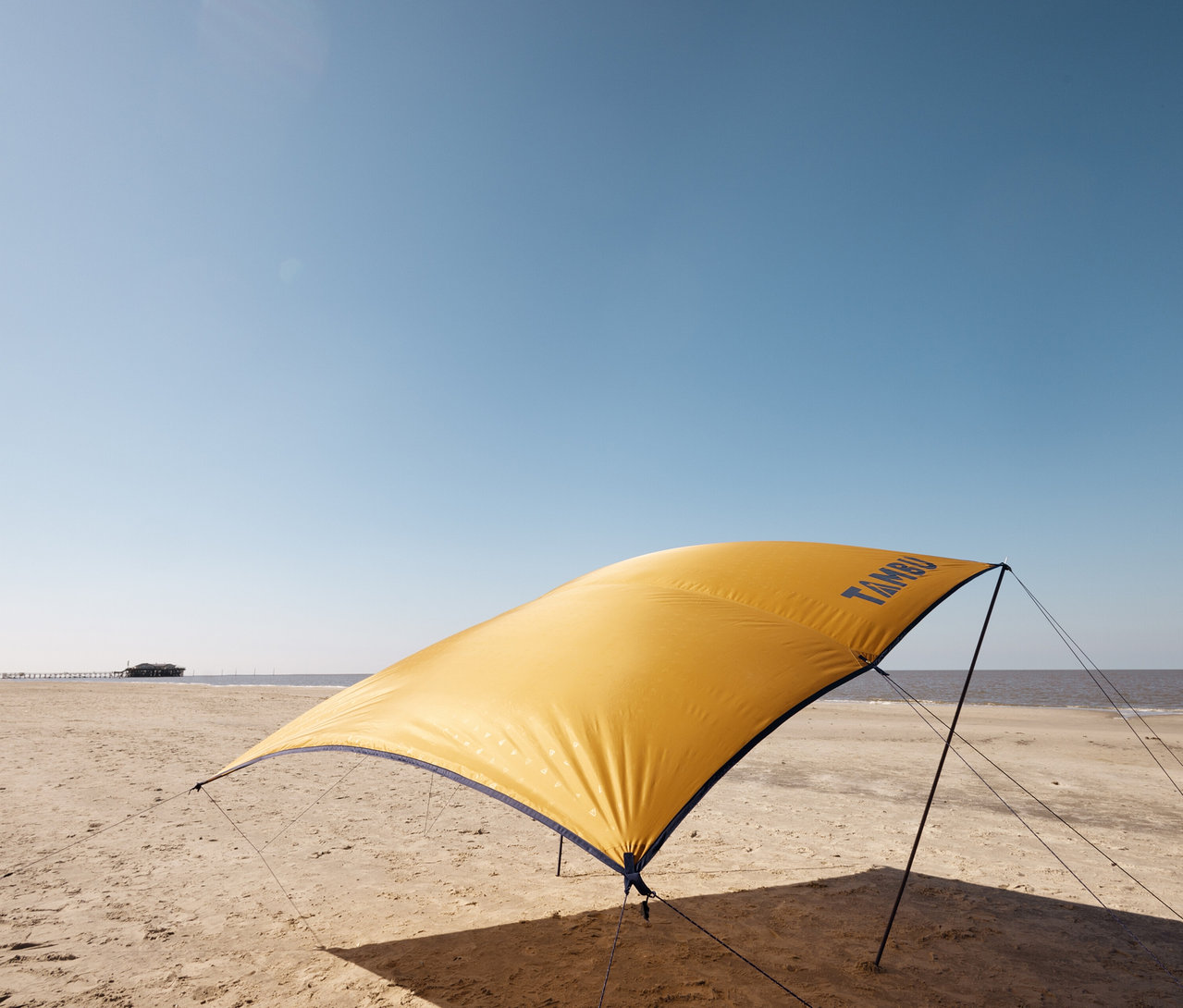 Gelbes Tambu »CHADA« Tarp/Sonnensegel steht am Strand.