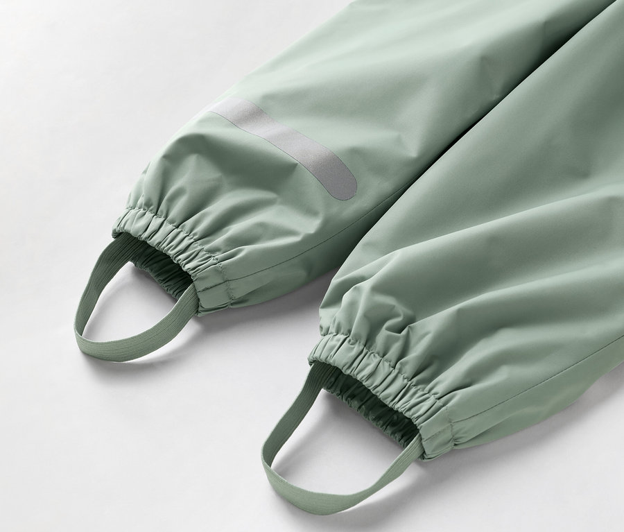 Nahaufnahme der Unterseite einer hellgrünen Hose mit elastischen Bündchen und Fußschlaufen.