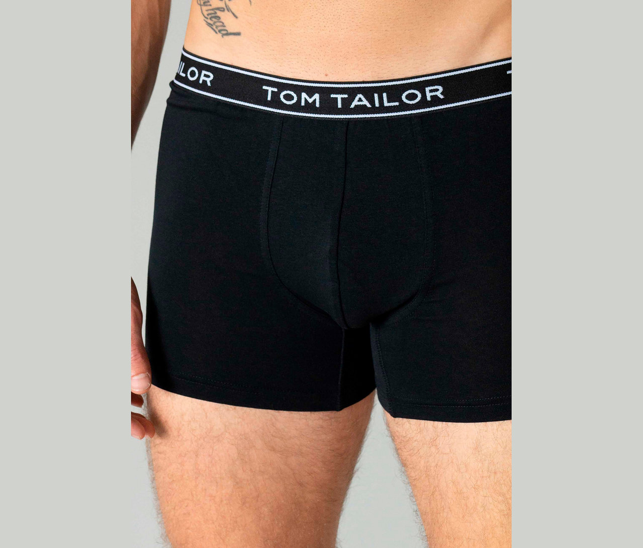 Nahaufnahme eines Mannes, der schwarze Boxershorts der Marke Tom Tailor trägt.
