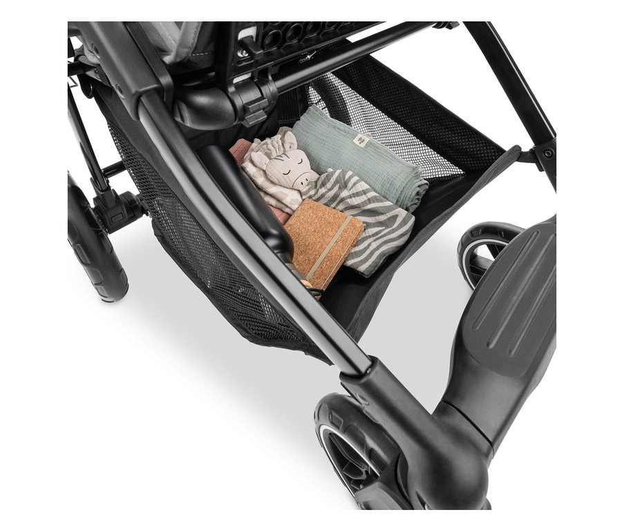 In einem schwarzen Kinderwagenkorb liegen ein Stofftier-Zebra, ein Notizbuch und Stoffwindeln.