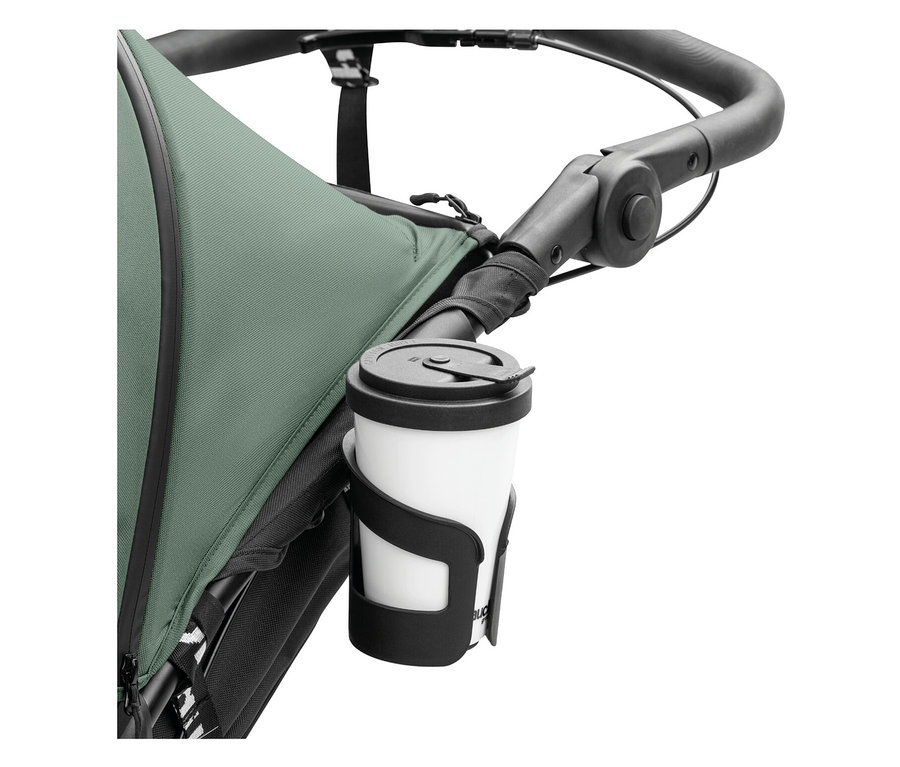 Ein weißer Becher mit schwarzem Deckel befindet sich in einem schwarzen Becherhalter, der an einem Kinderwagen befestigt ist.