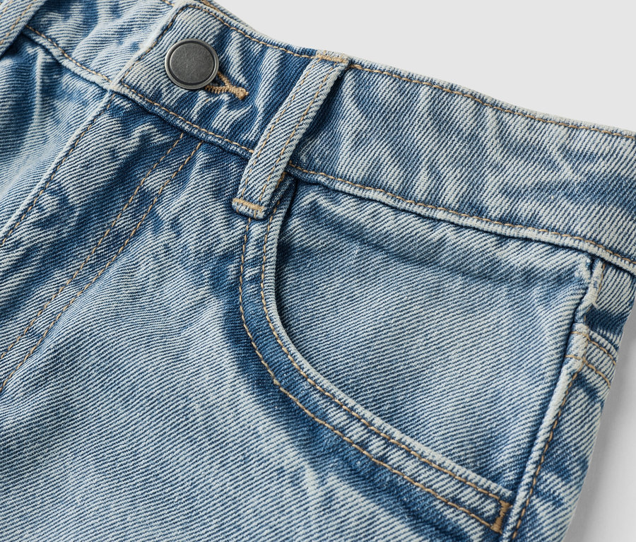 Nahaufnahme einer hellblauen Jeans mit Knopf und Tasche.