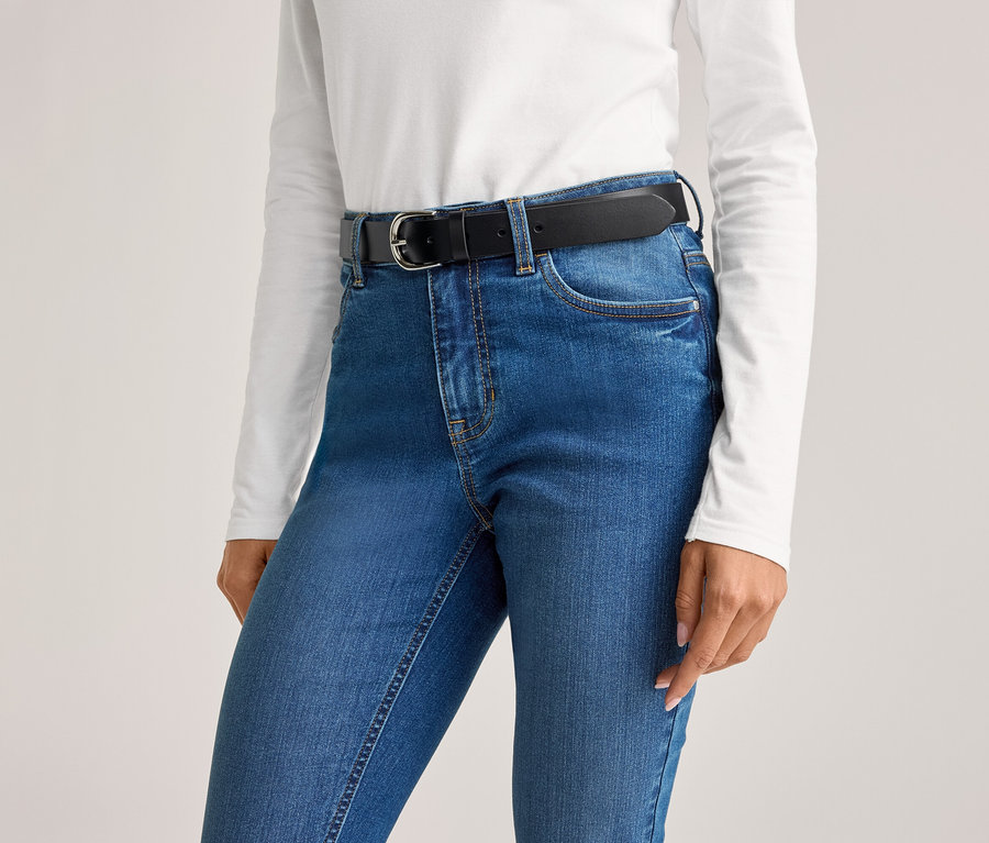 Eine Person trägt eine blaue Jeans mit einem schwarzen Gürtel und einem weißen Oberteil.