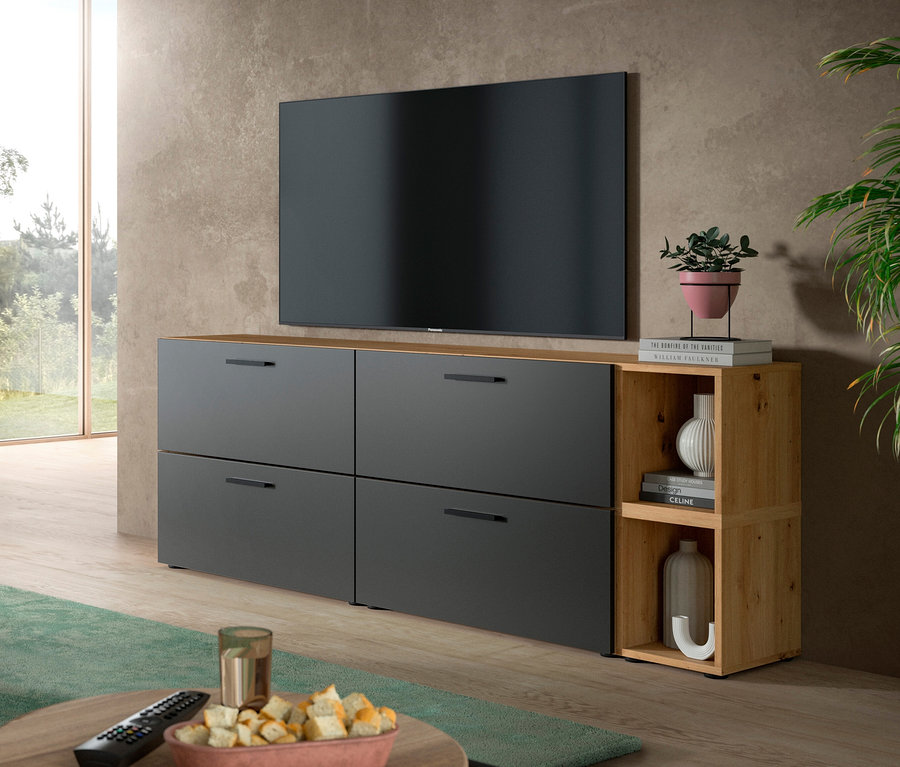 Graue xonox Wohnkombination »The One« mit Holzplatte und offenen Regalen unter einem Fernseher in einem Wohnzimmer. Auf einem Couchtisch stehen Snacks und eine Fernbedienung.