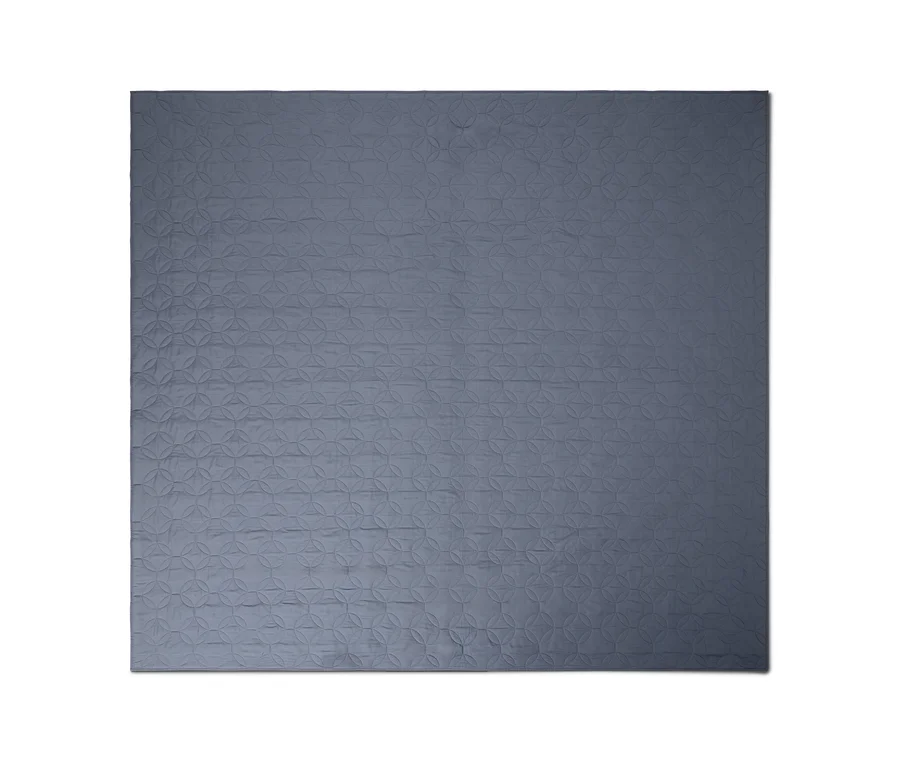 Blaugraue Steppdecke mit einem geometrischen Muster aus ineinandergreifenden Kreisen.