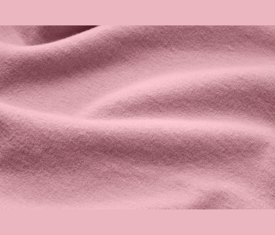 Nahaufnahme von weichem, rosafarbenem Stoff mit sanften Falten und Textur.