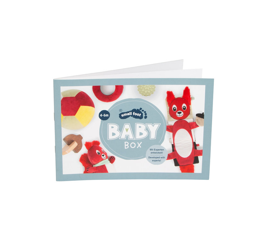 Offene Broschürenhülle für eine „small foot BABY BOX“ mit Illustrationen von Babyspielzeug: ein rot-gelber Ball, ein roter Ring, ein hellgrüner strukturierter Ball, ein hölzerner Pilz-Beißring und zwei rote Eichhörnchen-Plüschtiere. Text: „4-6m“ und „Mit Experten entwickelt!“.