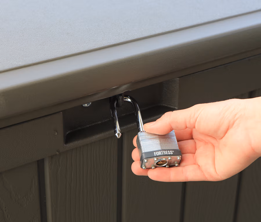 Eine Hand hält ein Vorhängeschloss an einer braunen Kissenbox (ca. 440 l).