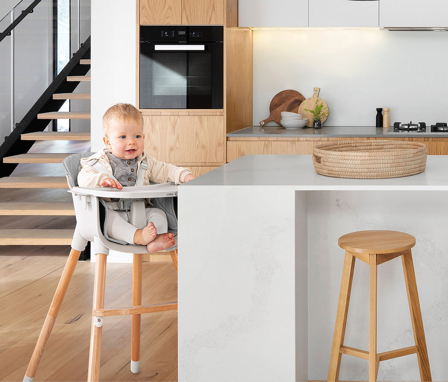 Ein Baby sitzt in einem roba 2-in-1-Hochstuhl »Style Up wood« in einer modernen Küche.