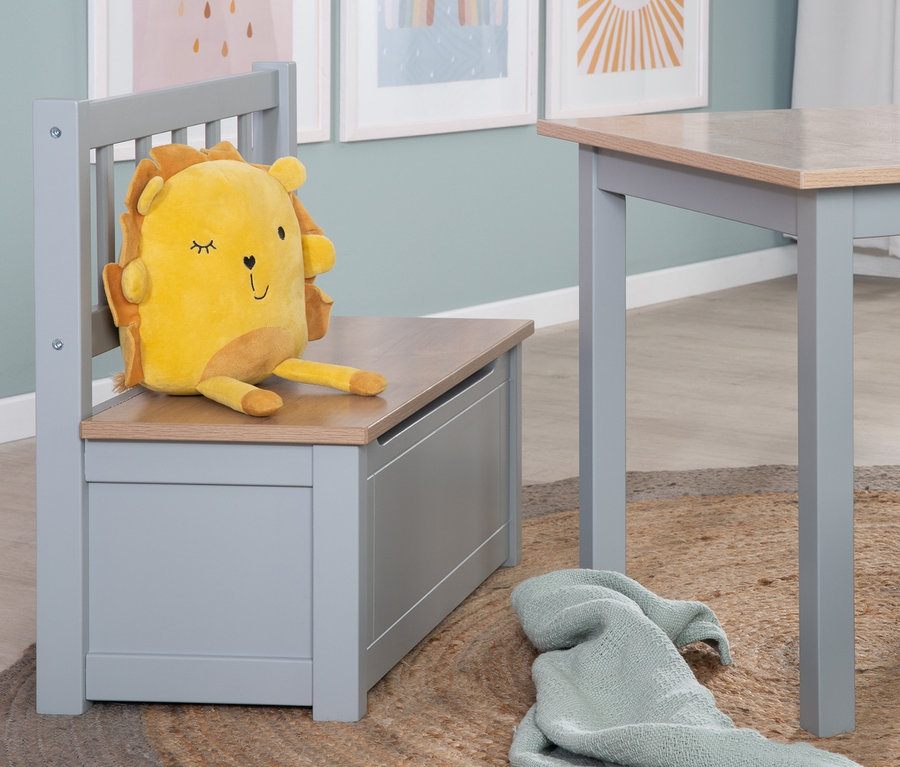 Gelbes Löwenkuscheltier sitzt auf roba Kindertruhenbank »Woody« neben Tisch auf Jute Teppich.