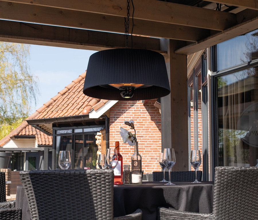 Schwarzer Sunred-Hänge-Heizstrahler »Halogen Artix Basic« über einem Tisch mit Stühlen auf einer Außenterrasse.