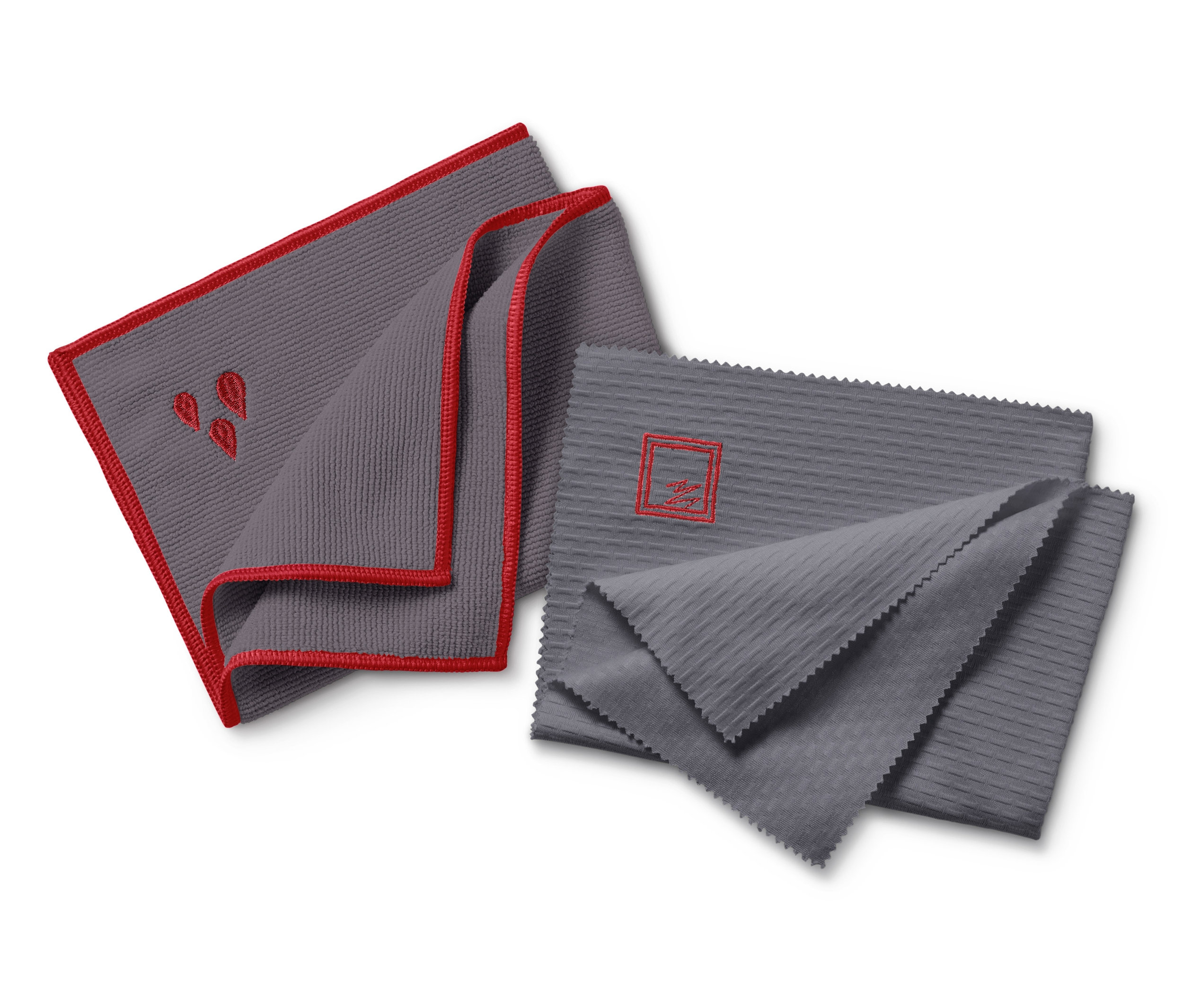 Zwei graue Tücher aus einem Reinigungstuch-Set. Ein Fenstertuch mit rotem Rand und Tropfenstickerei. Ein Poliertuch.