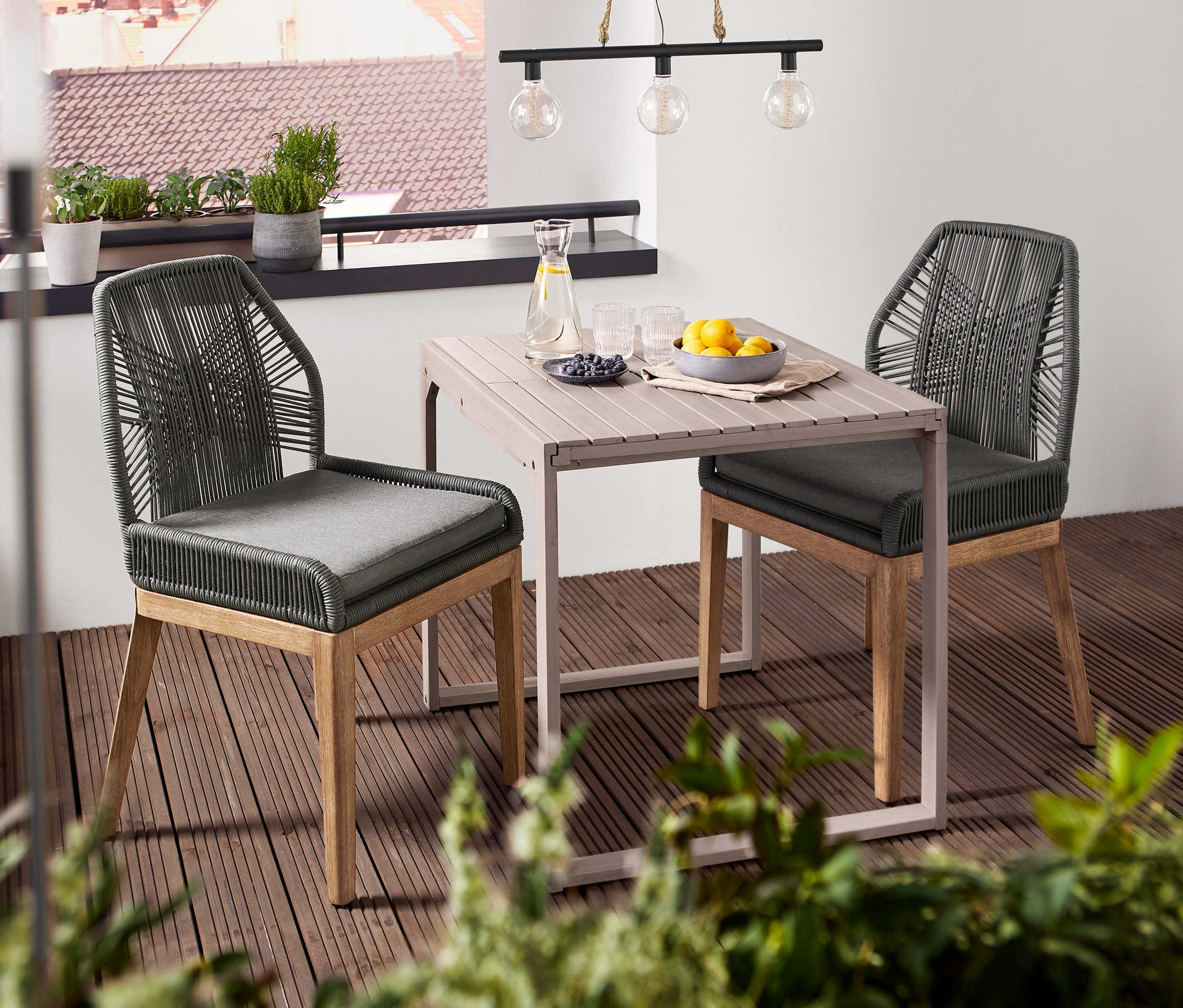 Zwei Stühle mit Textilgeflecht stehen an einem quadratisch kompakten Ausziehtisch »Leira«. Darüber hängt eine Solar-Hängeleuchte.