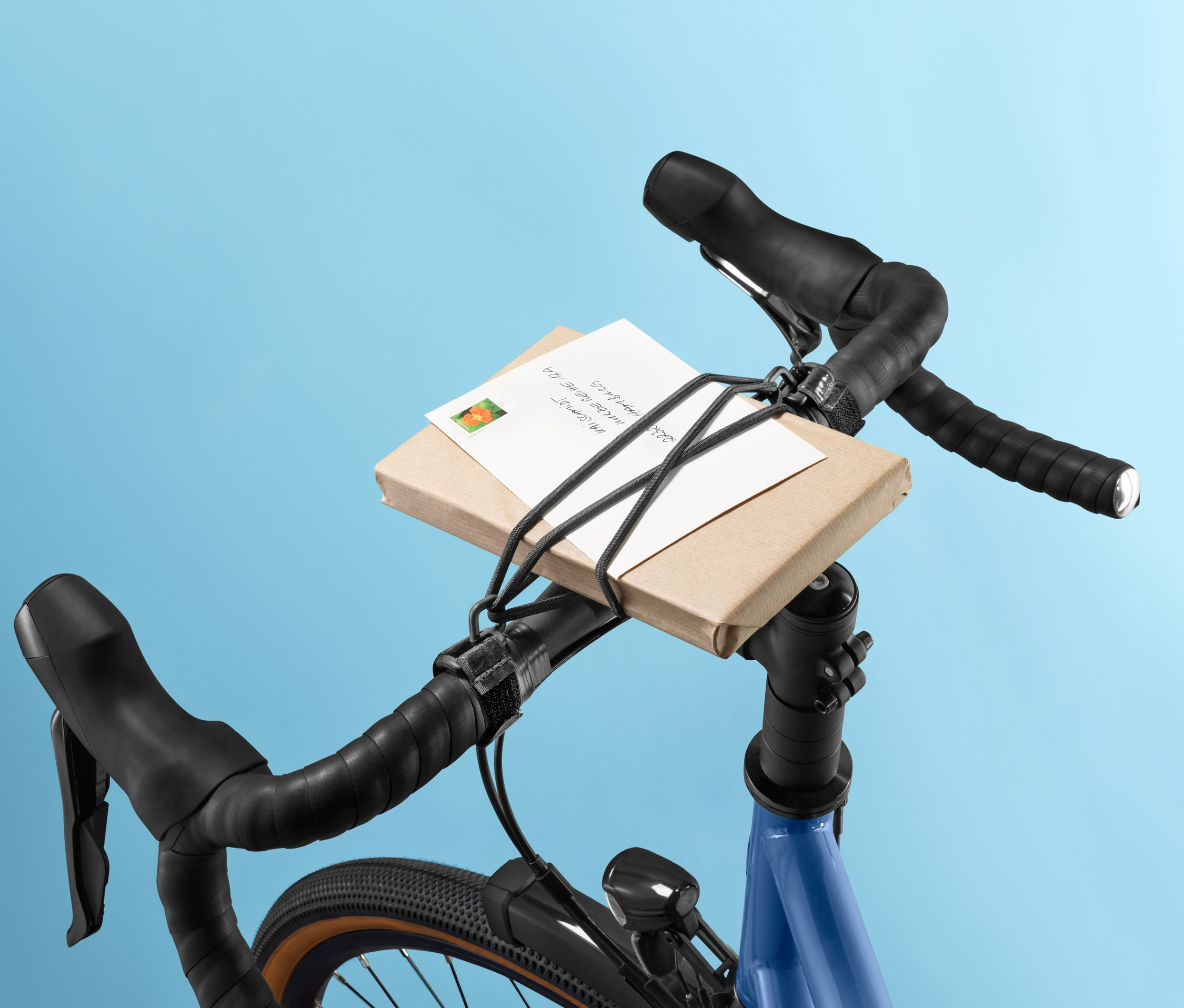 Paket am Fahrradlenker mit Lenkerspannband befestigt.