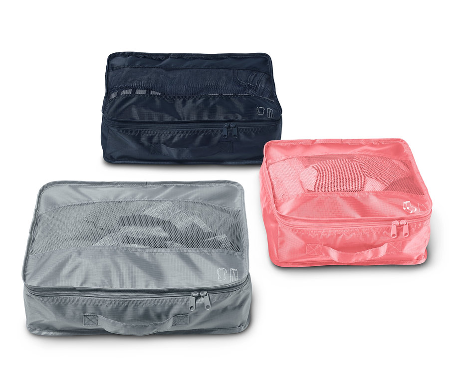 Drei Reise-Ordnungstaschen, eine blaue, eine graue und eine pinke.