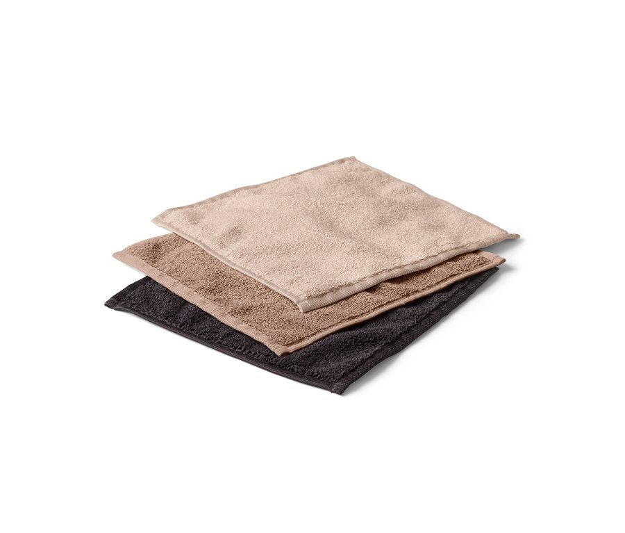 Drei Kosmetiktücher, braun, beige und schwarz, liegen übereinander.