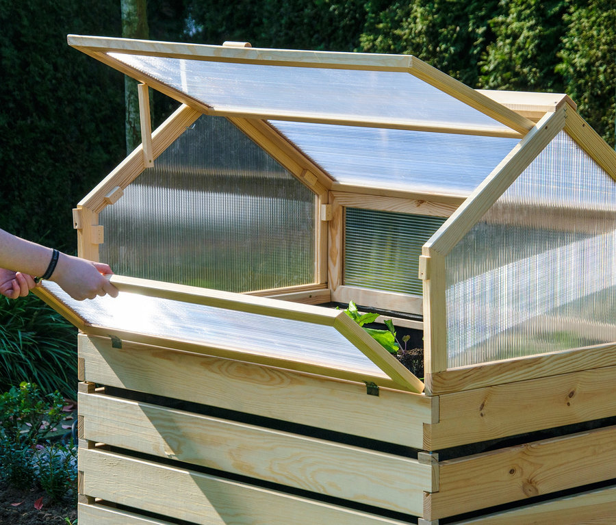Mann öffnet hölzernes Hochbeet „Hathi“ mit durchsichtigem Plastikdeckel.