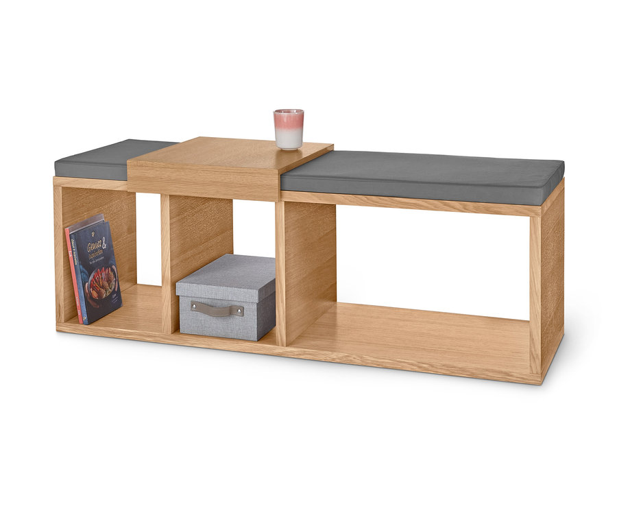 Sitzbank mit Polster, Buch, Kiste und Kerze.