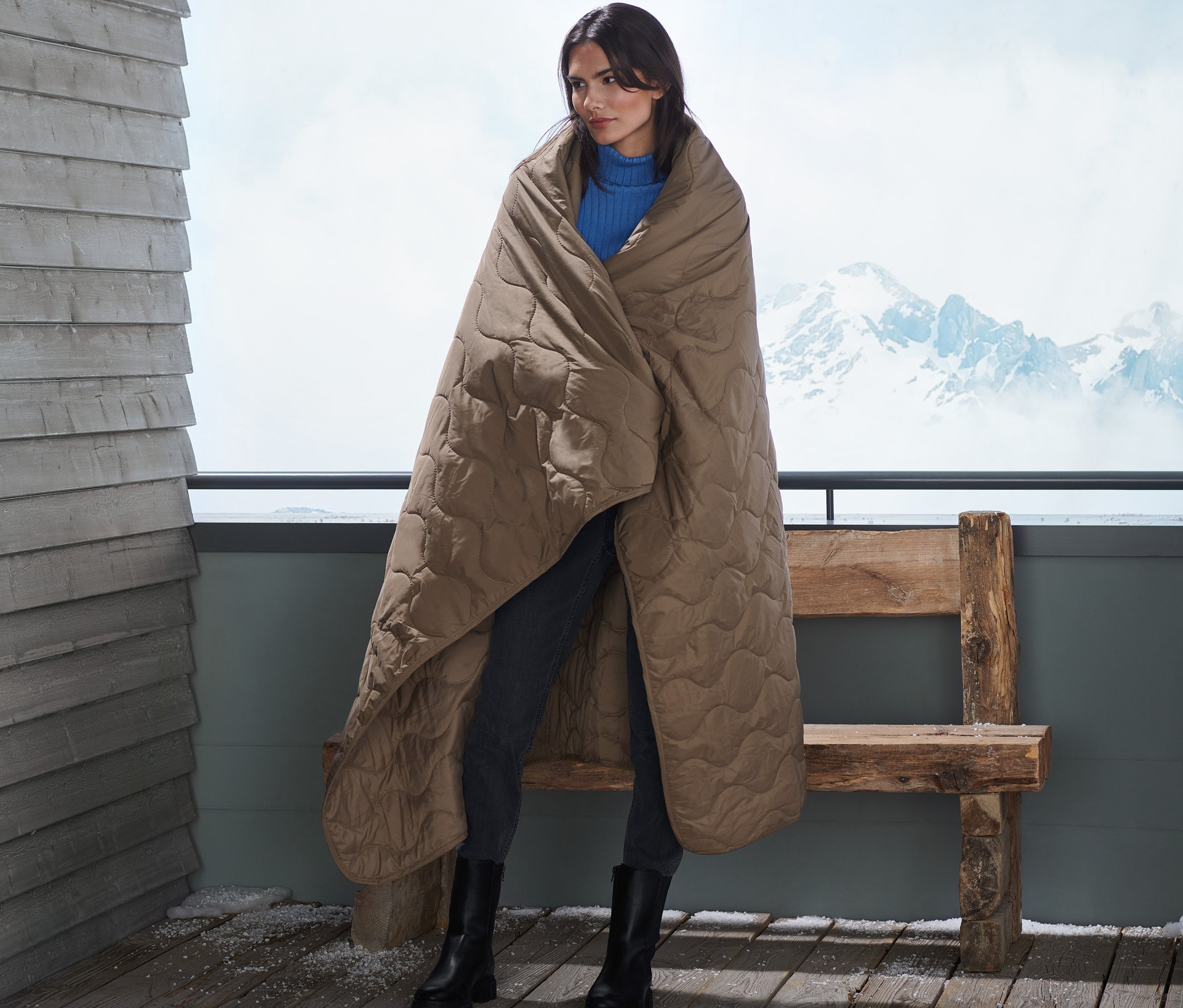 Frau steht auf Balkon gehüllt in Outdoor-Thermodecke.