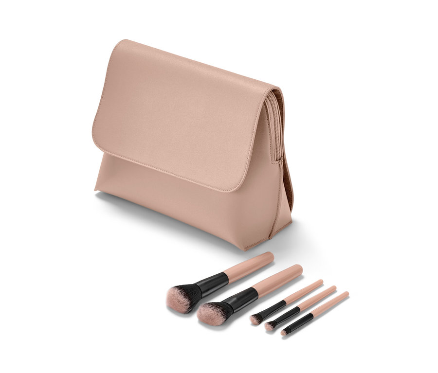 Eine rosa Kosmetiktasche und ein Set aus fünf Schminkpinseln liegen auf einem weißen Hintergrund.
